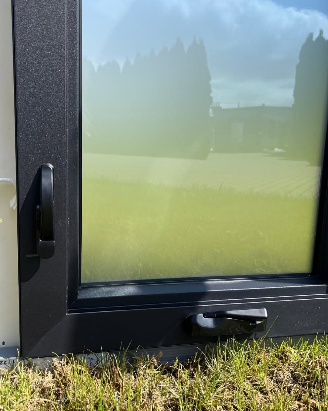 Folding crank operator at the sill and perimeter locking lever on a European outswing casement window in matte black