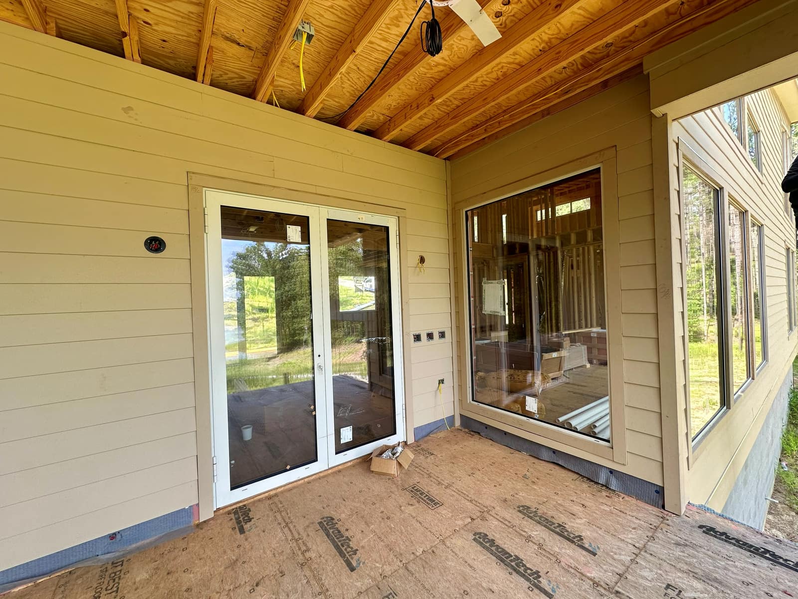 Covered porch elevation after siding - patio doors alongside fixed glazing.