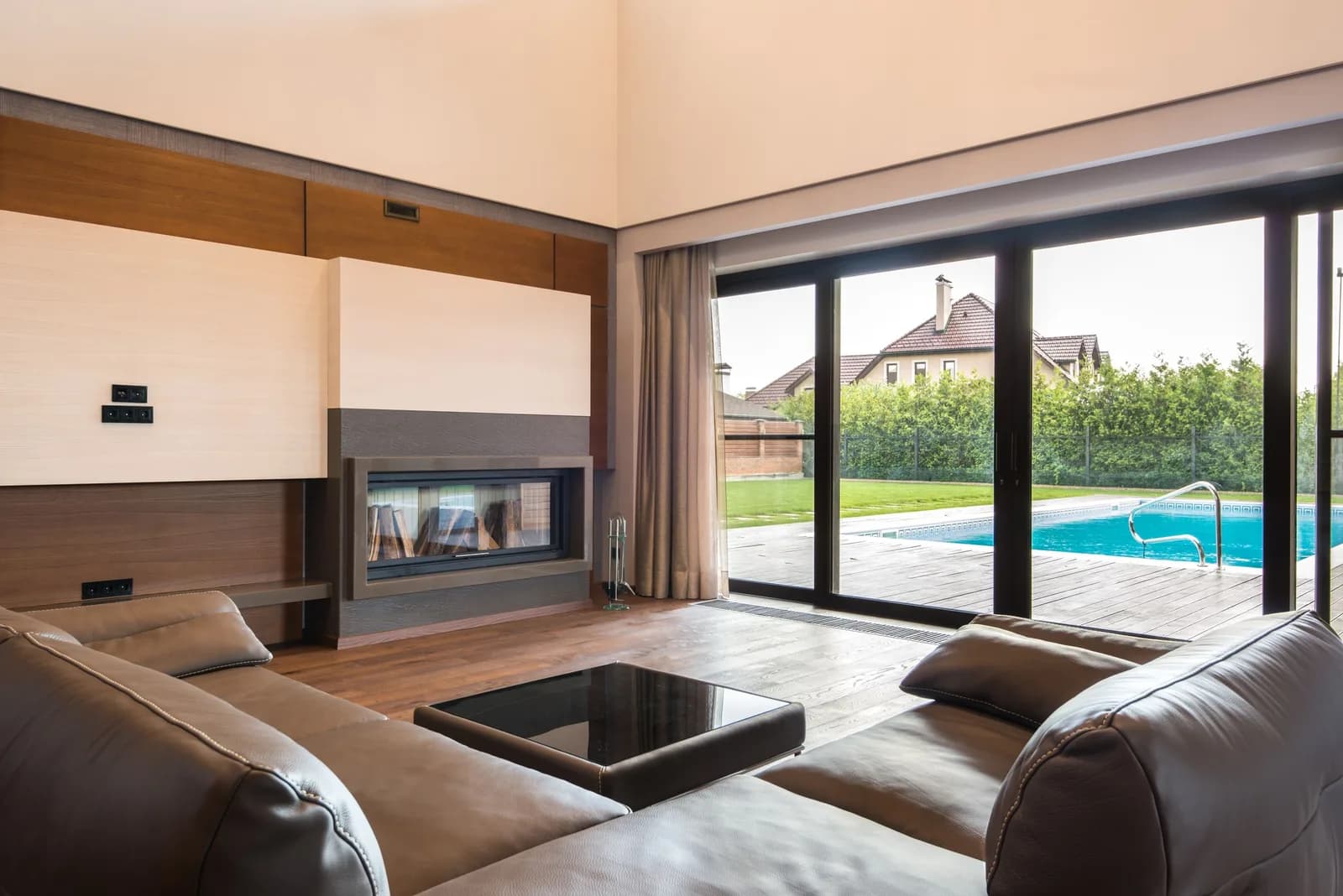 Living room with a large black-framed sliding glass wall opening to a pool terrace